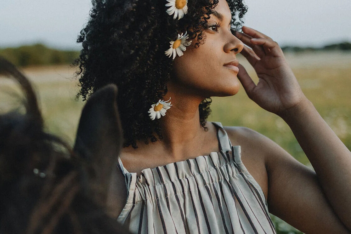 ecommerce growth strategies with Conrado - Girl in a field with flowers in her hair standing next to a horse.